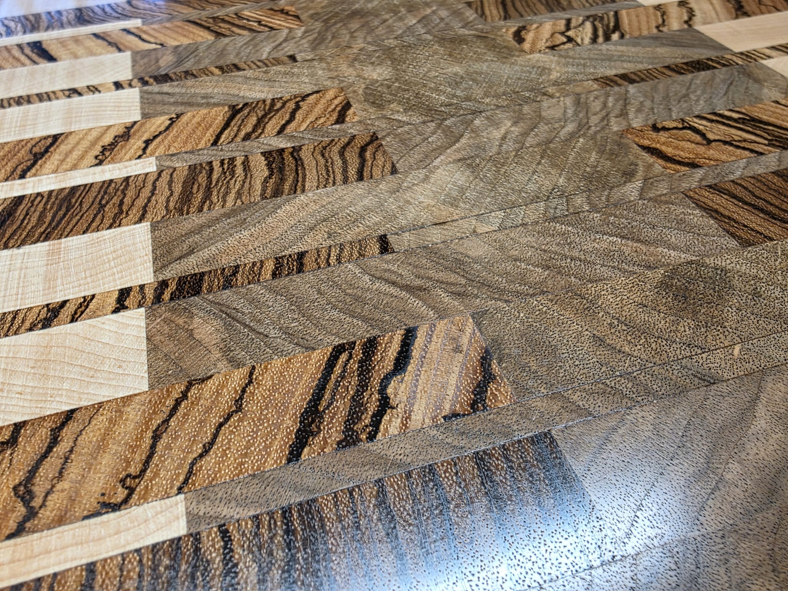 Gros plan sur les motifs et les veinages de la planche en zébrano, noyer et érable