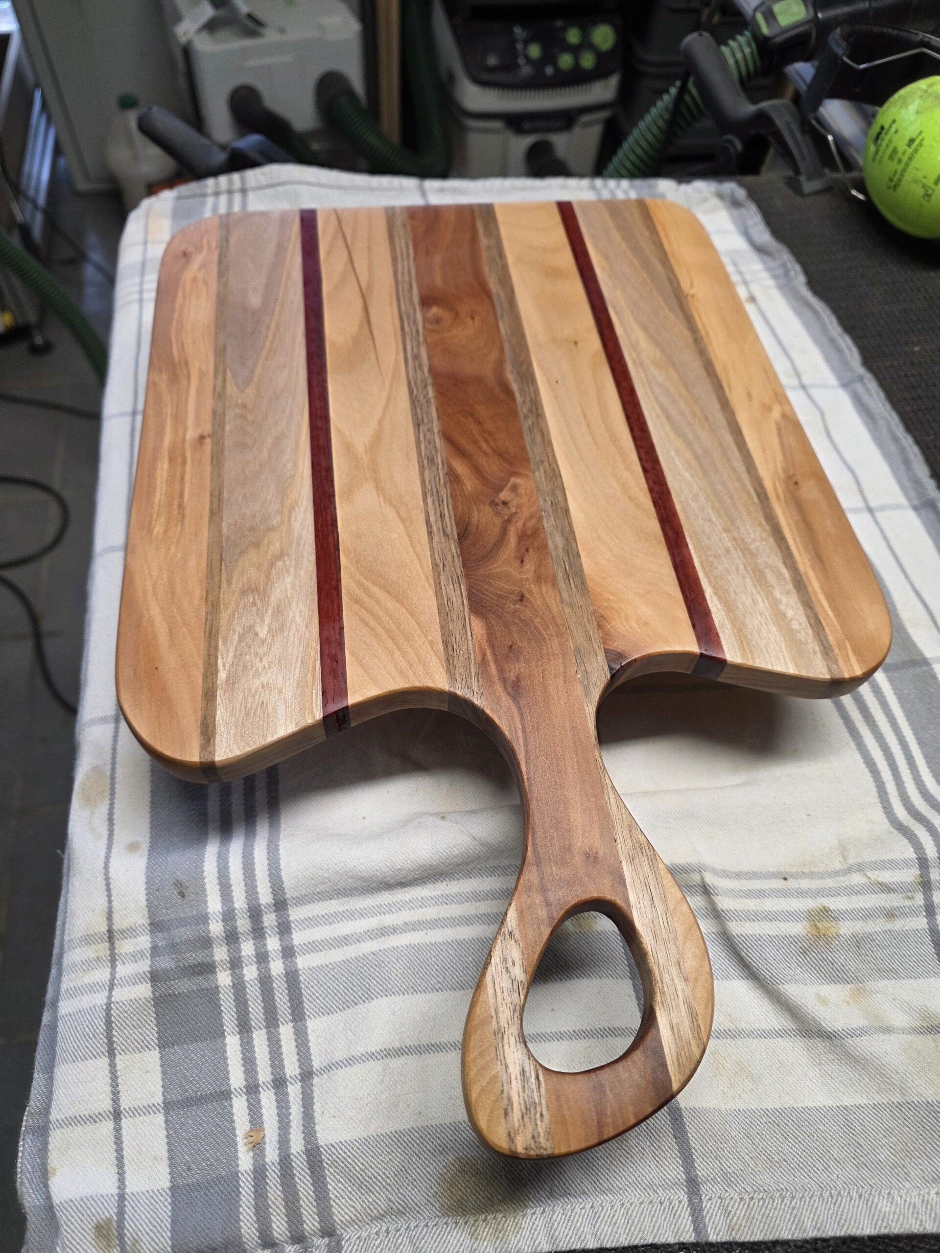 Planche de présentation à poignée ajourée, composée de bandes de bois aux couleurs contrastées